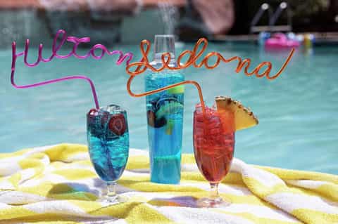 Colorful poolside cocktails with straws and 'Welcome Bachelorette' neon sign