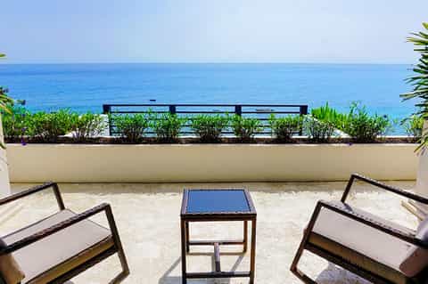 Oceanfront lounge area with black lounge chairs, blue cushions, and pristine sea view