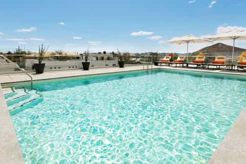 Resort rooftop pool with turquoise water, white umbrellas, and mountain views