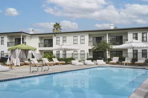 Resort pool with lounge chairs, umbrellas and white main building