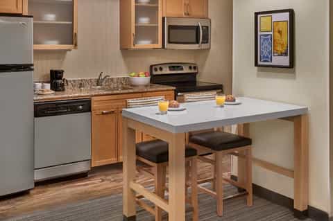 Apartment kitchen and dining area with wooden cabinetry, granite countertop, and breakfast seating