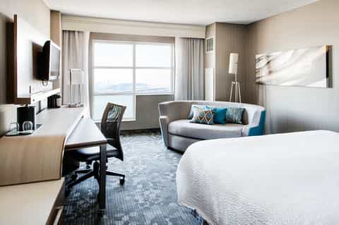 Hotel room with king bed, ocean view, desk, lounge chair, and contemporary décor