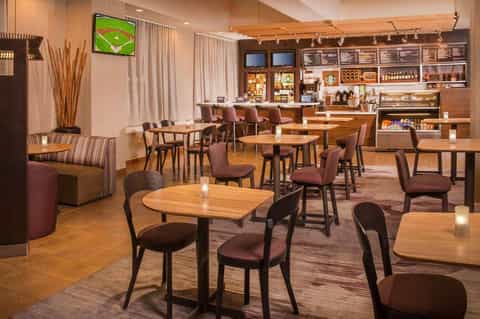 Hotel lounge and café with wooden seating, coffee bar, and sports entertainment display
