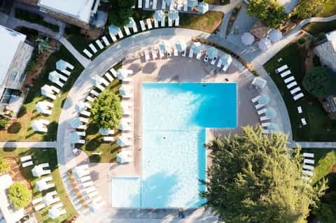 Aerial view of modern resort with two rectangular pools, white lounge chairs, and manicured landscaping