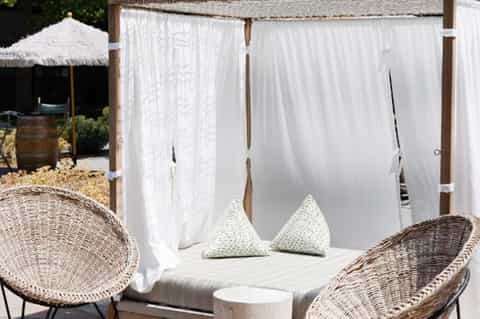 Outdoor daybed cabana with white flowing curtains and decorative pillows