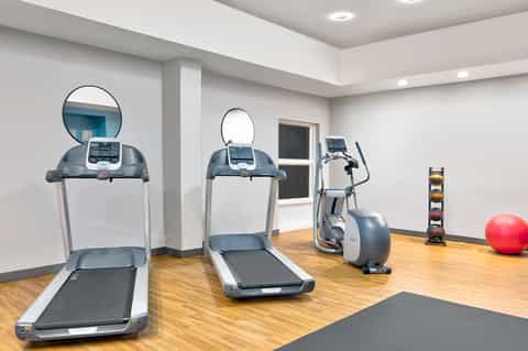 Bright fitness center with treadmills, exercise bikes, and cardio equipment