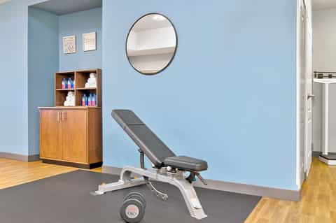 Spa treatment room with blue walls, weight bench, mirror, and wooden storage cabinet