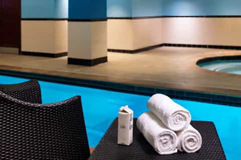 Pool deck area with stacked white towels and amenities displayed on black lounge chair