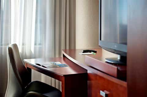 Hotel business desk with monitor, chair, and windows overlooking city skyline
