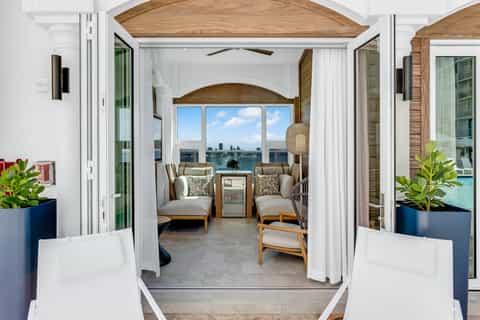 Oceanfront balcony room with comfortable seating, water views through arched windows