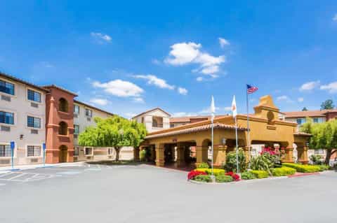 Spanish colonial-style resort courtyard with yellow buildings, red flowers, and central tower