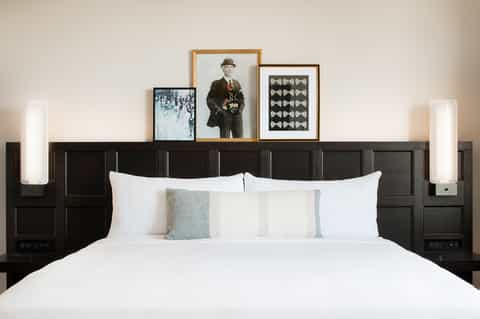 Upscale bedroom with dark wood headboard, white bedding, and framed wall art