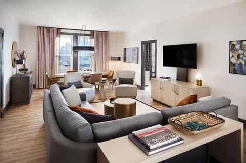 Luxury hotel suite with curved sofa, ocean view, modern furnishings and pink curtains