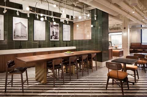 Contemporary lounge bar with green tile walls, wooden counter, and mid-century seating
