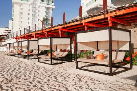 Beach cabanas with red structural framework and white fabric canopies