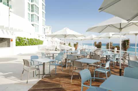 Elevated beach terrace with white umbrellas, modern seating, ocean view, and contemporary architecture