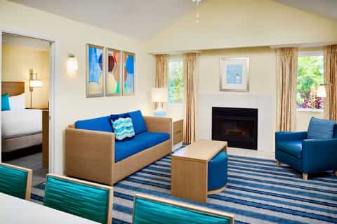Hotel suite with fireplace, sofa, armchair, and access to bedroom and patio