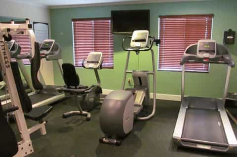 Fitness center with cardio equipment, treadmills, exercise bikes, and green accent walls