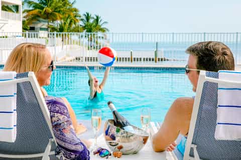 Couple relaxing by oceanview pool with champagne and beach ball