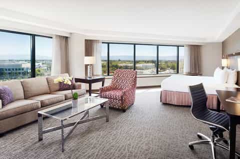 Luxury hotel suite with panoramic windows, elegant furnishings, and valley views