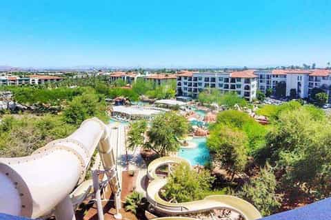 Aerial view of resort with water slides, pools, and multi-story buildings surrounded by landscaping