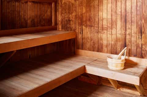 Wooden sauna interior with benches and traditional wooden bucket