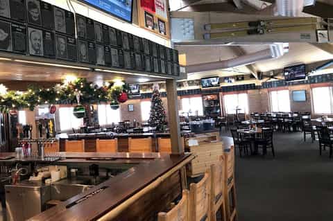 Sports bar restaurant interior with menu board, seating, and holiday decorations
