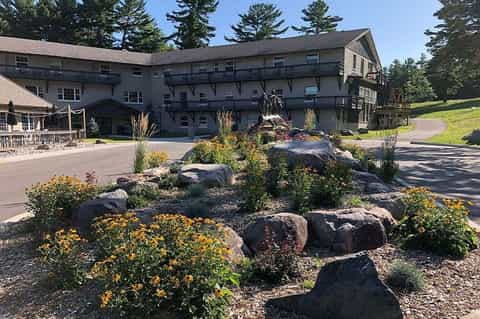 Large gray resort building with landscaped rock garden and yellow flowers