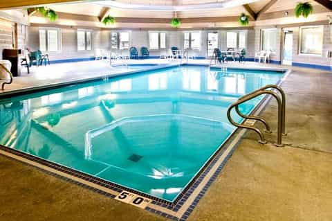 Indoor heated pool facility with skylights, lounge seating, and spa hot tub in spacious hall