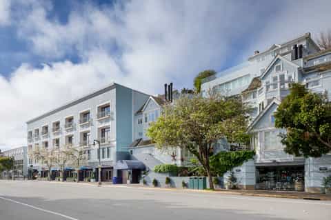 Beachfront hotel buildings with blue and white exterior, retail shops, and landscaped street-level promenade
