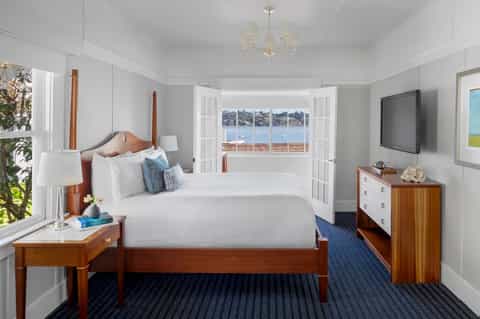 Coastal hotel bedroom with twin beds, ocean view windows, wooden furniture, and nautical décor
