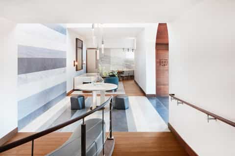 Modern hotel corridor with minimalist design, striped marble walls, white round table, and wooden railings
