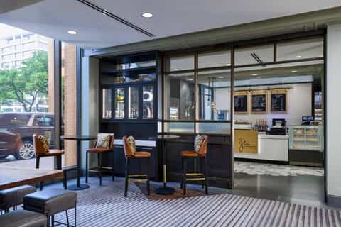 Hotel cafe interior with modern seating, floor-to-ceiling windows, and service counter