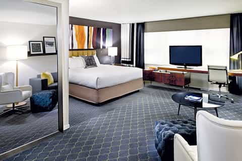 Modern hotel suite with king bed, workspace, and contemporary furnishings