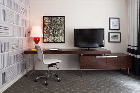 Home office with dark desk, TV, bookshelf, and red desk lamp