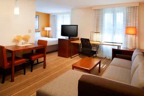 Hotel suite with wood furniture, sofa, work desk, and modern amenities