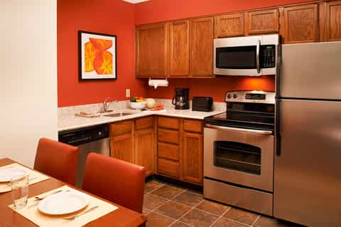 Modern kitchen with red walls, stainless steel appliances, and wooden cabinetry