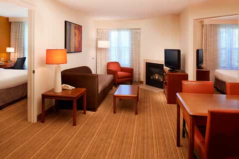 Suite living room with fireplace, orange accents, sofa, and bedroom access