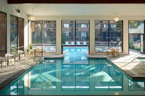 Indoor lap pool with large windows overlooking outdoor pool area