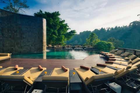 Luxury infinity pool with waterfall, mountain jungle views, and lounge chairs