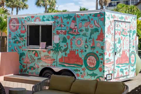 Colorful food truck with turquoise and coral beach-themed artwork and serving window.