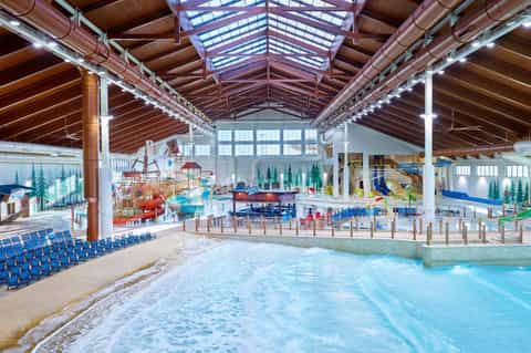 Indoor water park with wave pool, slides, and covered ceiling structure
