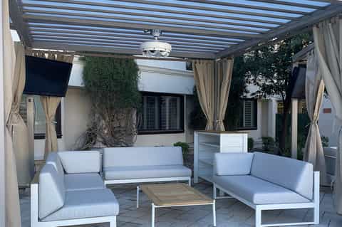 Modern patio with pergola, white sofas, planters, and smart shade system