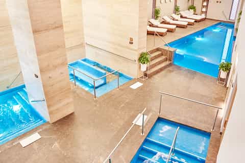 Indoor spa area with multiple hot tubs, marble columns, and heated pool facilities