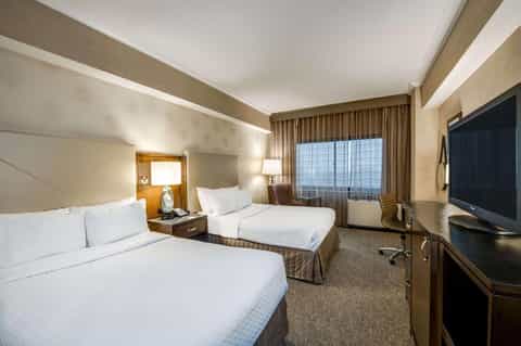 Modern hotel room with two queen beds, TV, and large window