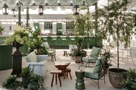 Elegant outdoor terrace with green striped awning, potted plants, and modern seating