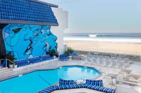 Resort pool deck with blue artwork mural, striped loungers, and direct beach access
