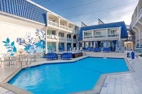 Indoor hotel pool with blue accents, striped lounge seating, mural artwork, and multi-story building