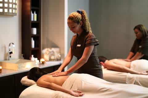 Spa massage therapist treating client on white table in modern wellness center