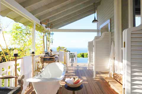 Outdoor deck with freestanding bathtub, ocean view, and white railings at coastal villa